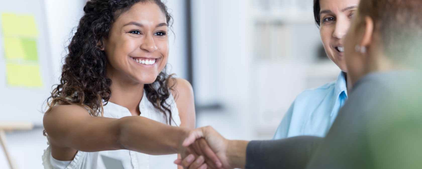 young woman shakes hands with the community manager of a coworking space
