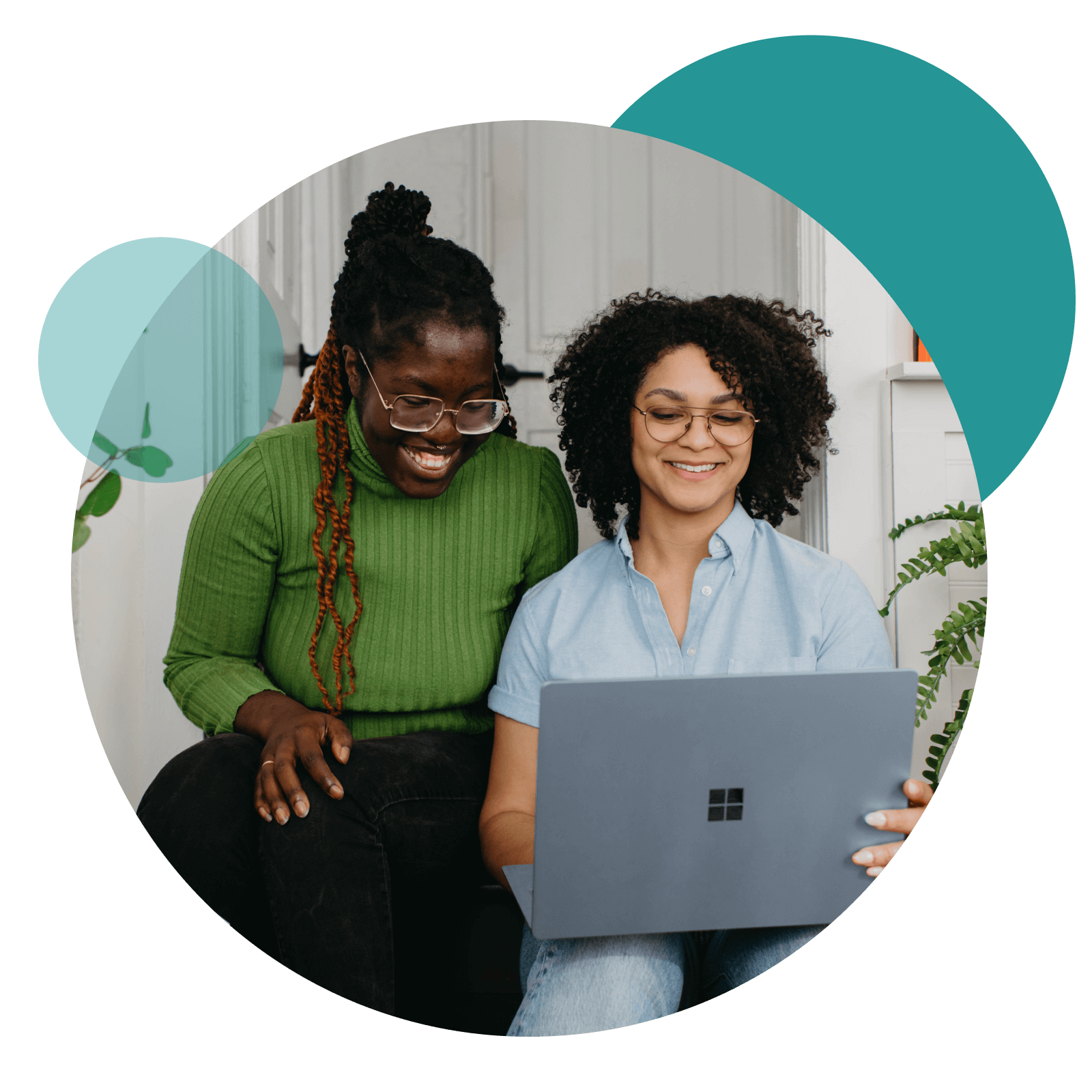 Two women smile and look at laptop in a coworking space